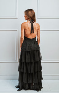 Femme debout et de dos montrant le dos ouvert d'une robe noire et longue