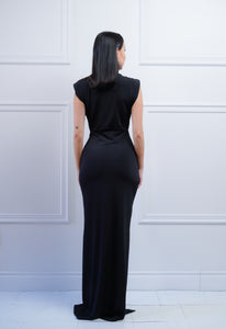 Femme debout tournée montrant le dos de sa longue robe noire sans manches