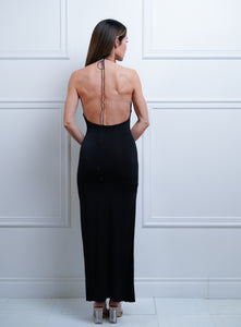 Femme debout portant des talons hauts et une robe noire longue montrant son dos 