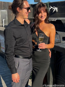 femme tenant une coupe de champagne et portant une robe noire accompagné d'un homme habillé pour une soirée chic